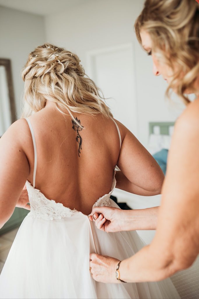 Bride zipping up her dress at Navarre Beach, Florida Wedding