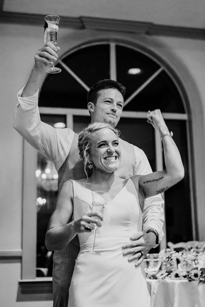 bride and groom share fun moment drinking champagne and laughing at wedding reception 