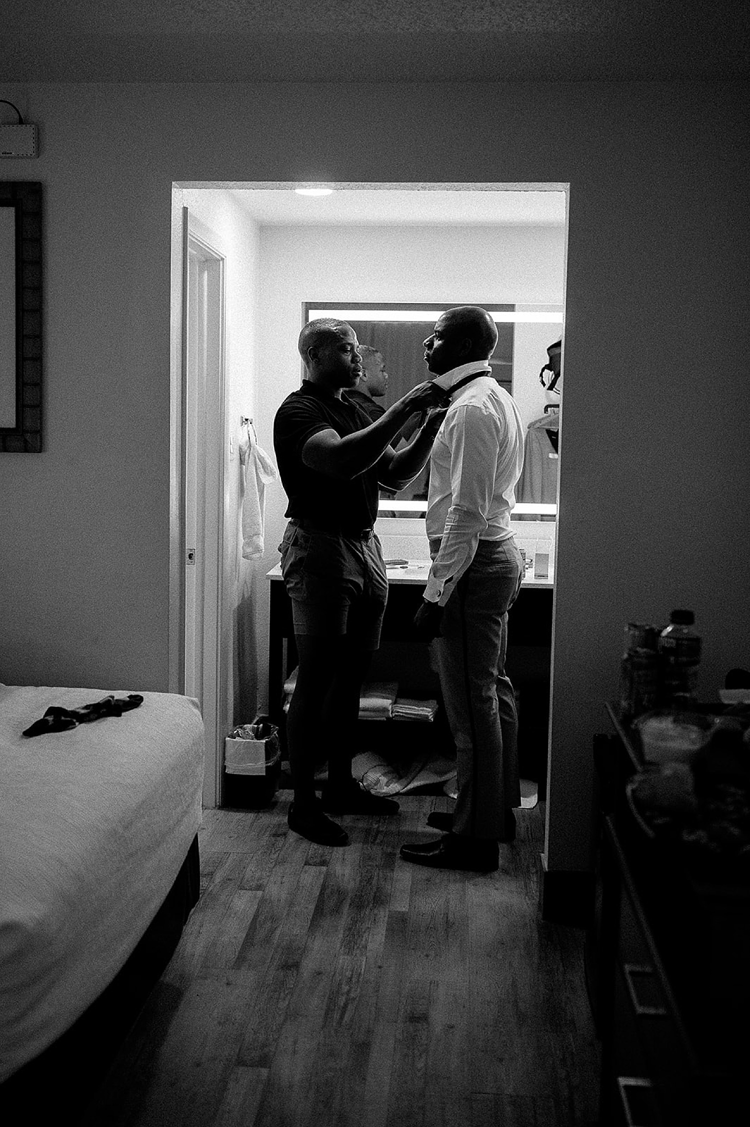 Groom and groomsmen finalize getting ready in hotel room in Destin Florida with wedding photographer