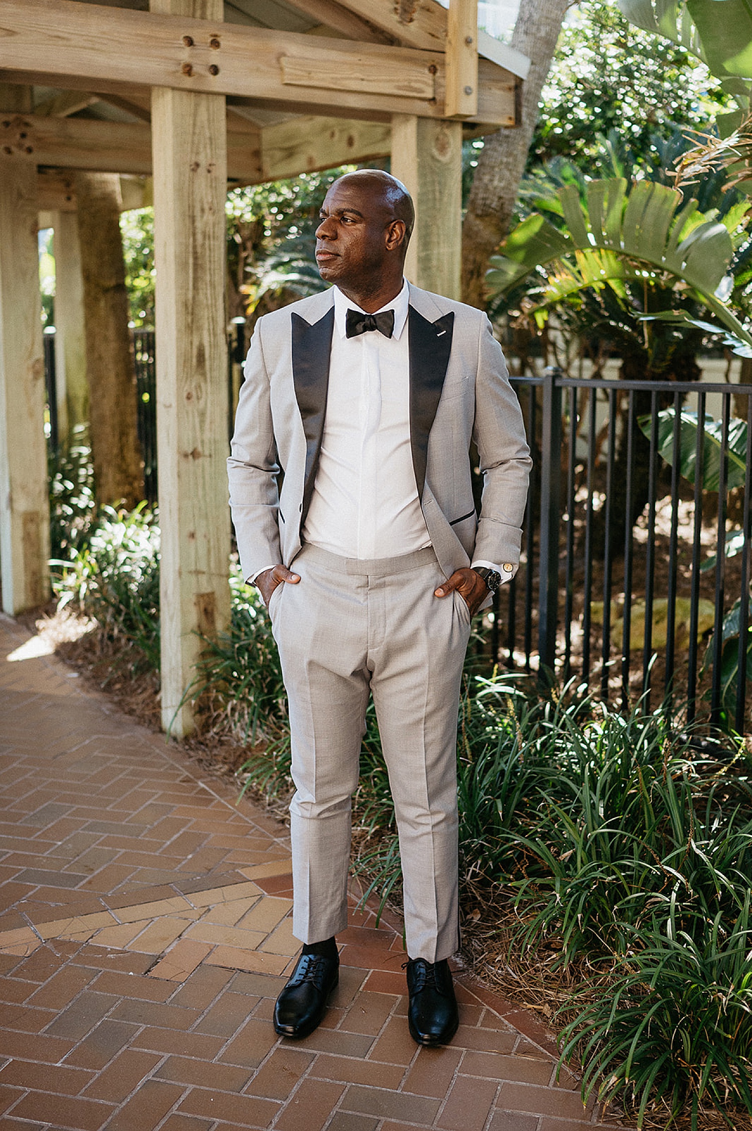 GRoom wearing light gray suit and black dress shoes with a black bowtie