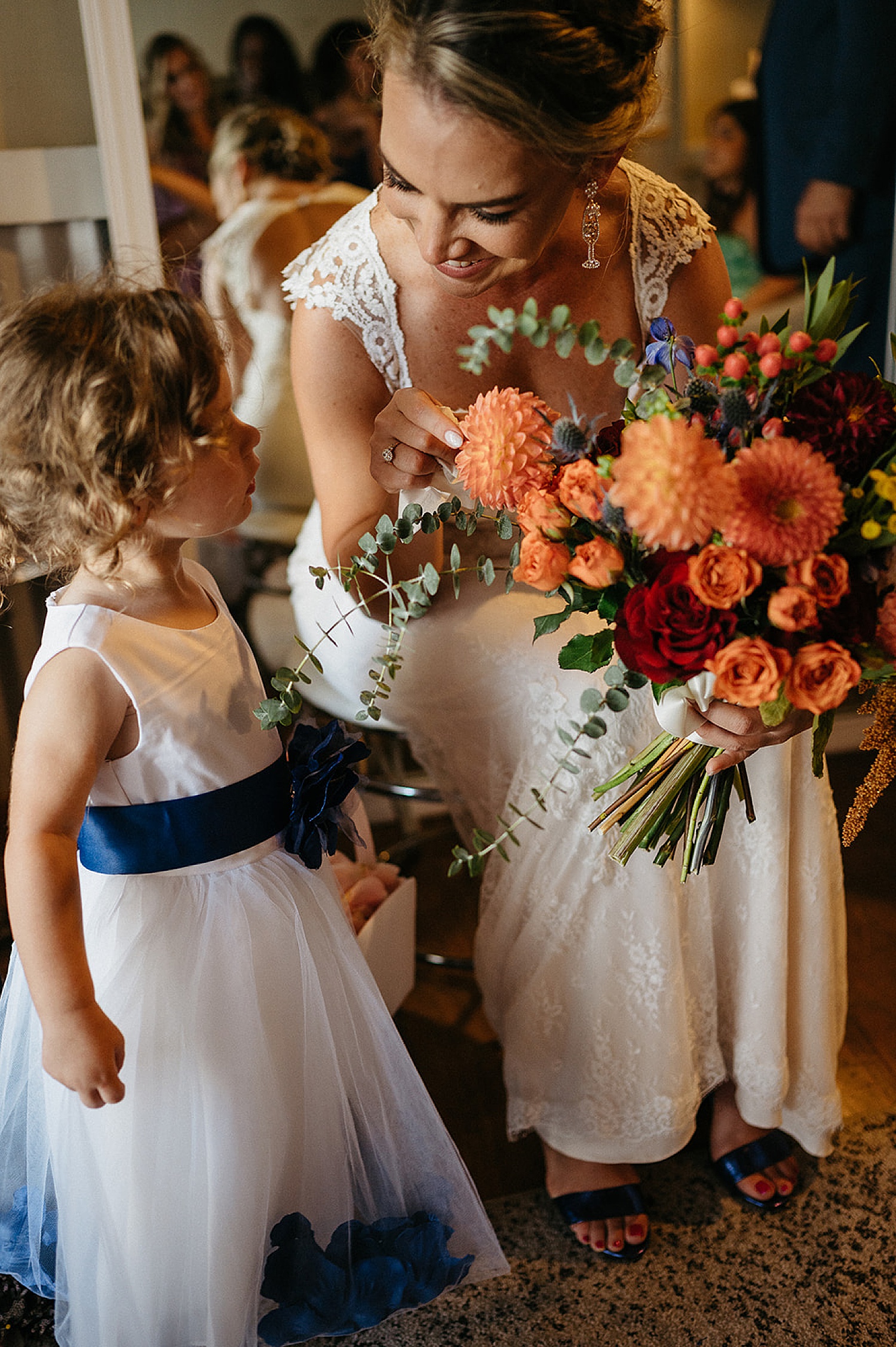 Bride shows flower girl wedding bouquet while wearing champagne earrings