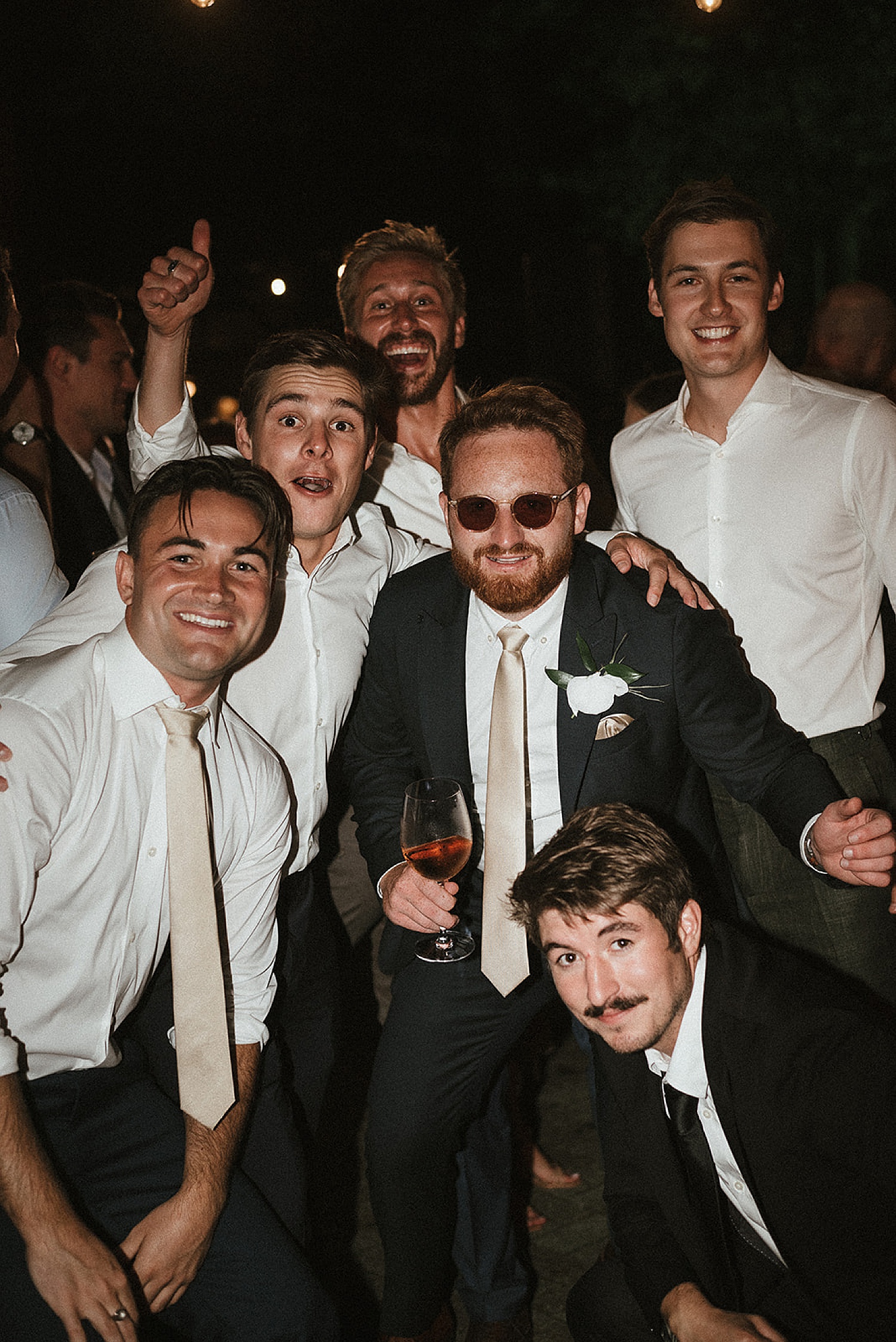 Groomsmen Dancing at wedding reception wearing sunglasses and holding drinks 