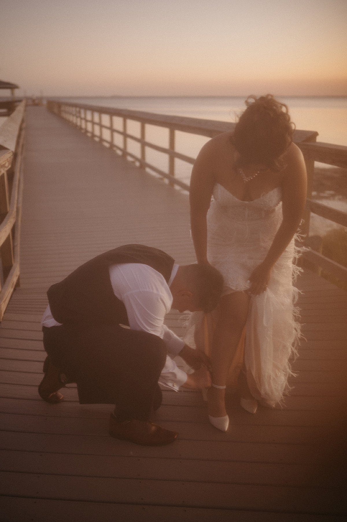 groom putting on brides heels at sunset by Emily burns photo