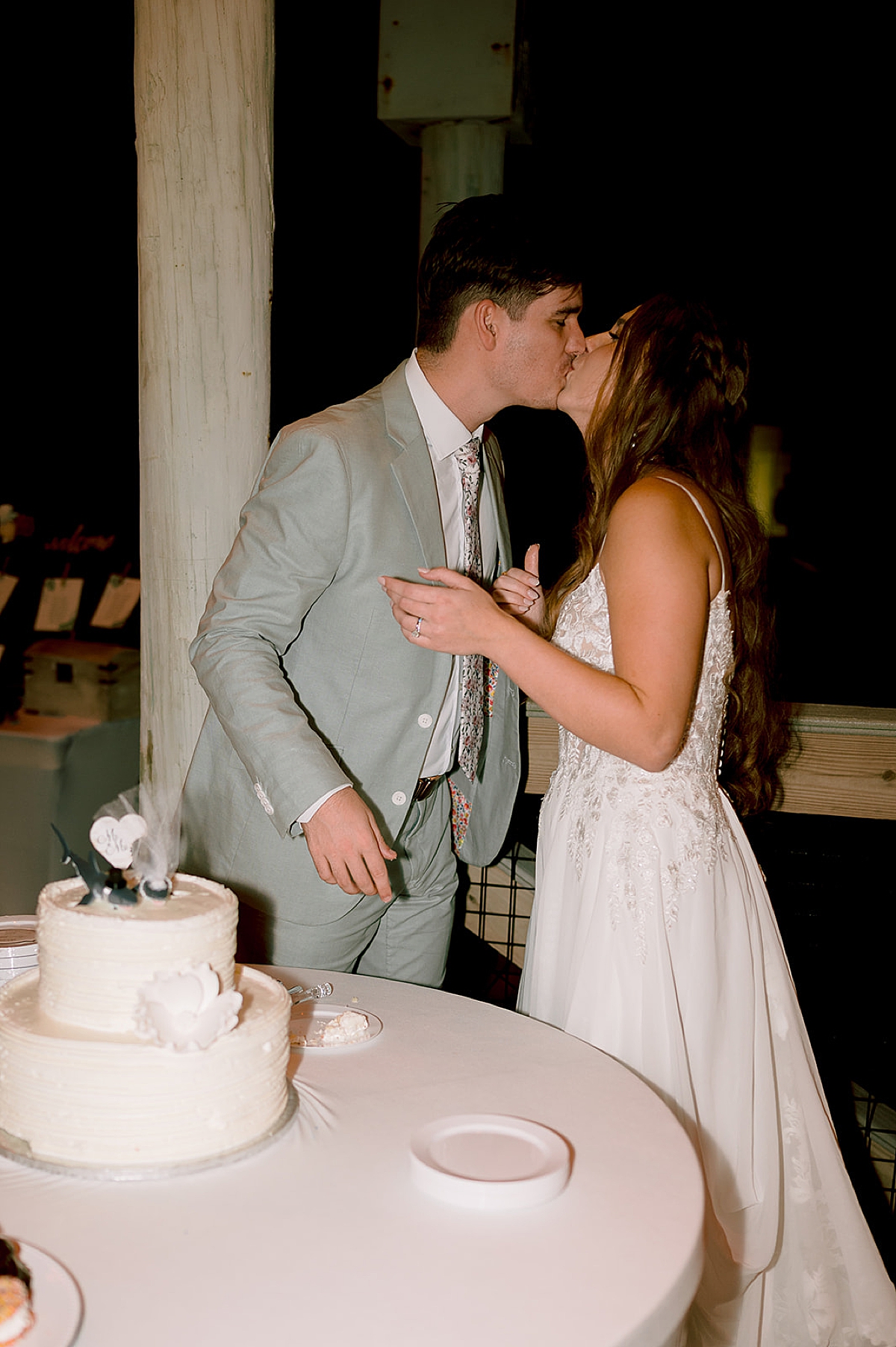 bride and groom kiss after cutting cake at reception by florida wedding photographer 
