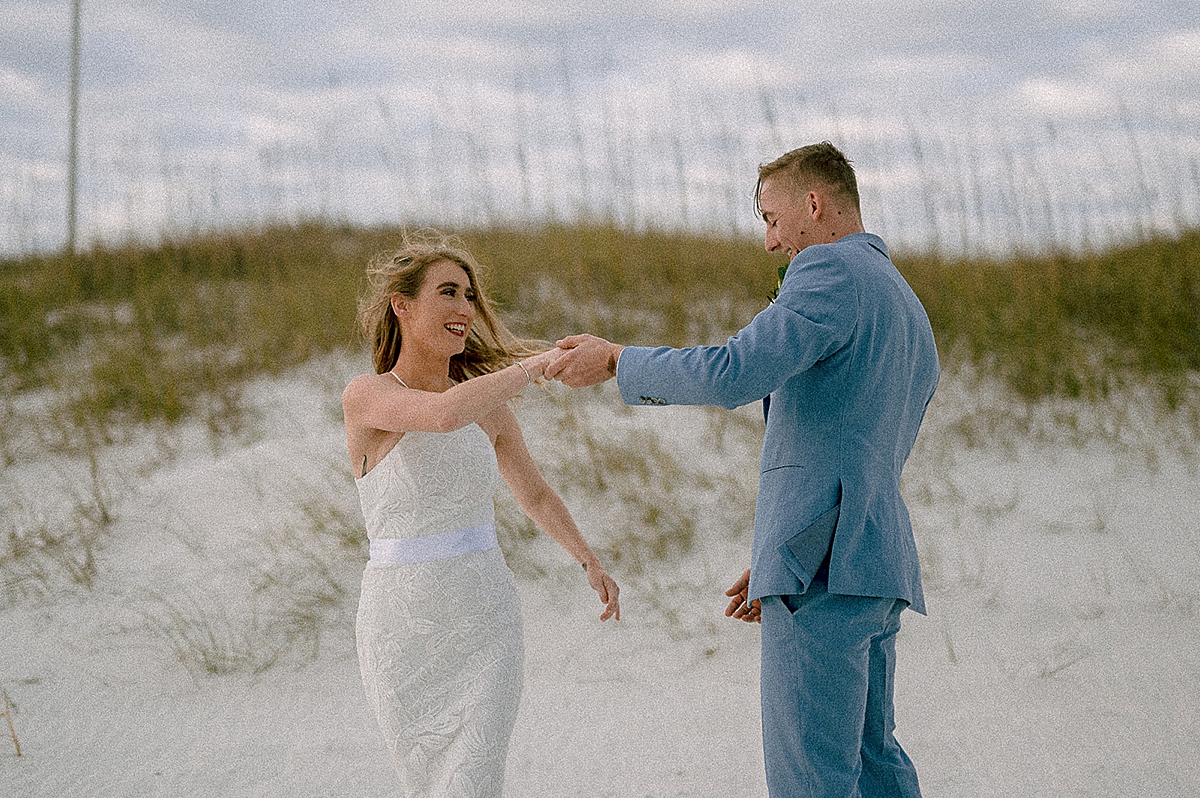 groom twirling new wife after first look on the beach by pensacola elopement photographer 